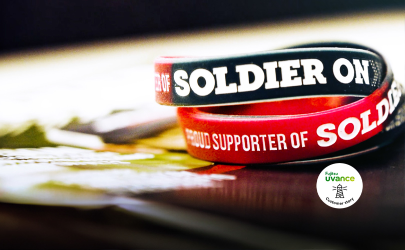 En inzoomad bild av ett armband på marken som har texten "Supporter of Soldier On".
