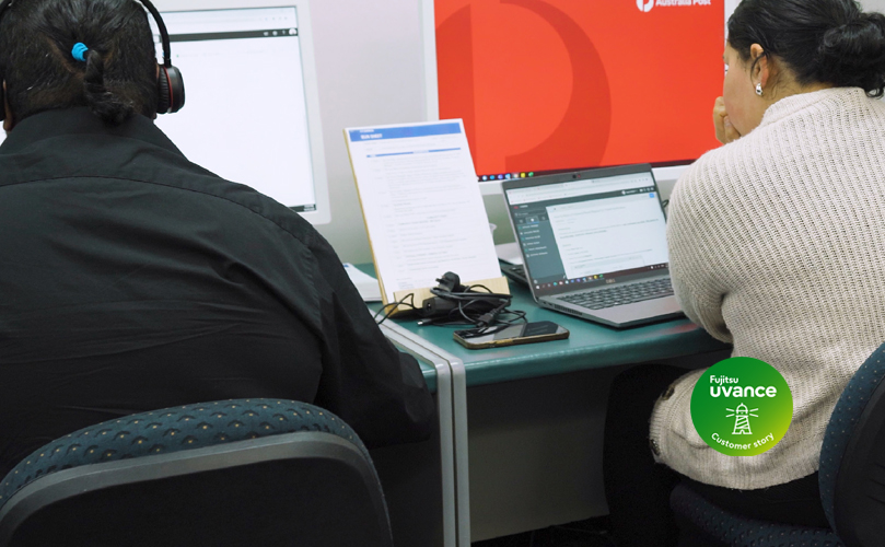 Två personer som arbetar vid ett skrivbord på sina datorer