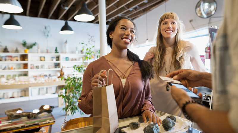 Women are talking with a shop clerk at the checkout counter