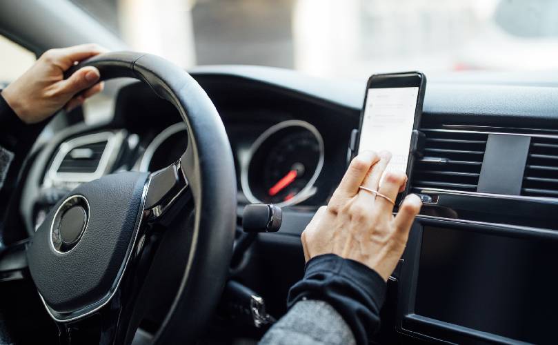 A person sitting in a car touching his phone