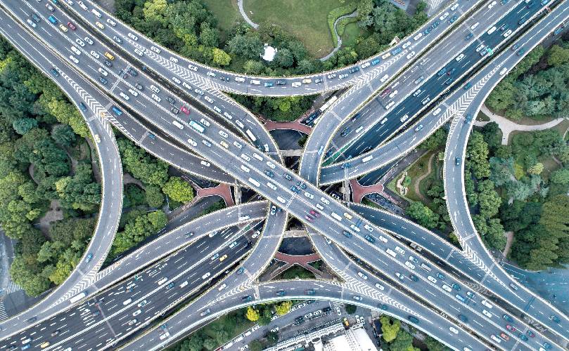 Daily Overhead view of a complex highway intersection, surrounded by green areas