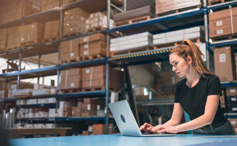 A woman who uses a laptop in a warehouse