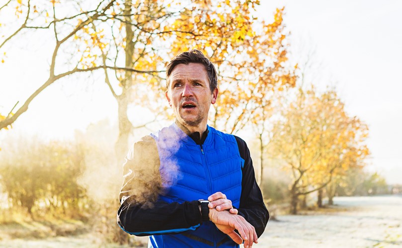  Man exercising outside, on a sunny day and wearing a smart device on his left wrist