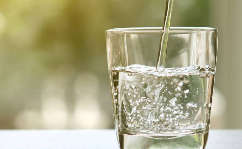  Water being poured on a glass on a blurred background 