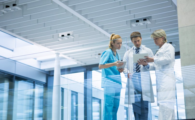 3 people talking holding a tablet at a healthcare facility