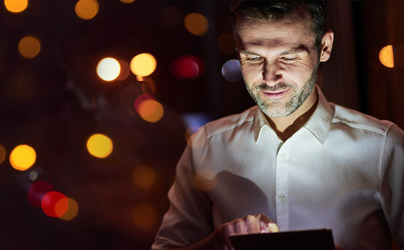 An adult man is looking at digital device at night