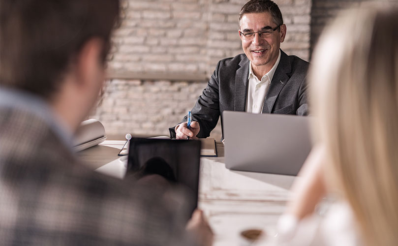 Smiling businessman having a meeting with his customers in the office