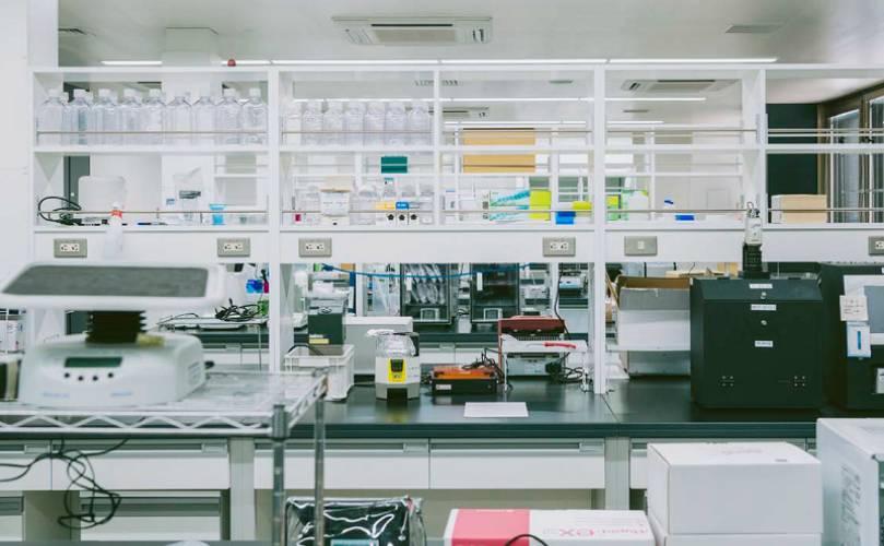 A scientific research laboratory with benches, analysis equipment and rows of bottles