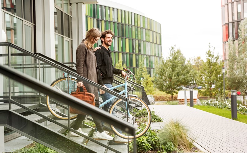 Two people walking down stairs with a bicycle.