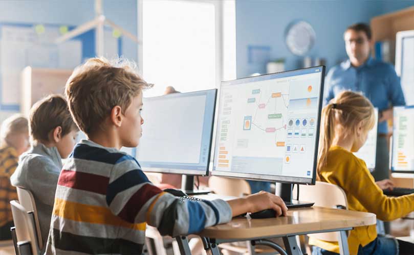 Schulkinder lernen Informatik an Computern im Klassenzimmer