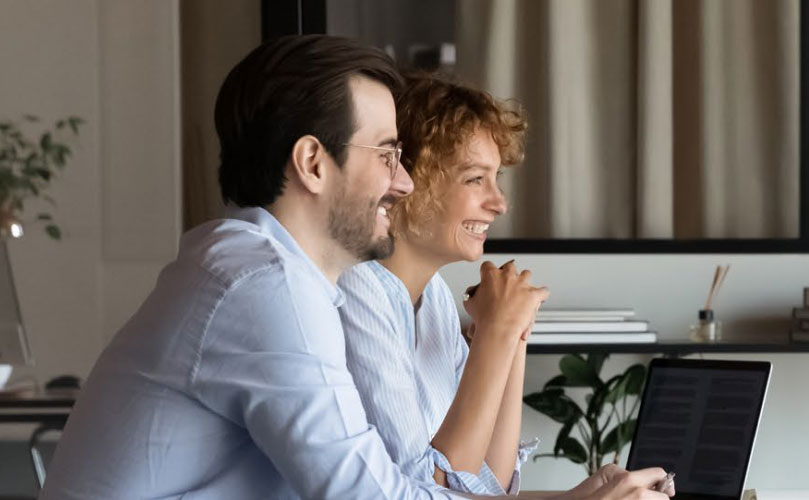 Zwei Personen arbeiten gemeinsam am Laptop im Büro