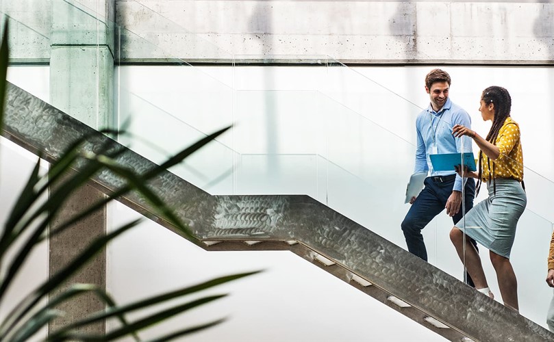 A group of professionals walk up a modern staircase.