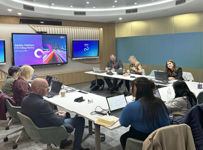 Ability Matters members sat in discussion in a large meeting room.