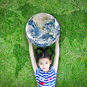 芝生に寝転がり地球を抱きかかえる笑顔の女の子