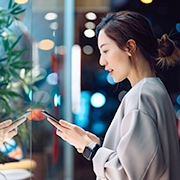 夜景を背景にスマートフォンを操作する女性の横顔の画像