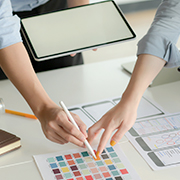 デザイン作業で色のパレットとタブレットを使用する手元の画像