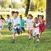 芝生の上を元気に走る複数の子供たちの画像
