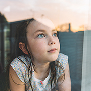 窓の外を眺める幼い女の子、物思いにふける