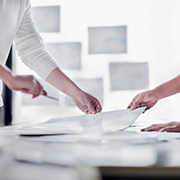 テーブルの上で資料を共有し合う人々の手元