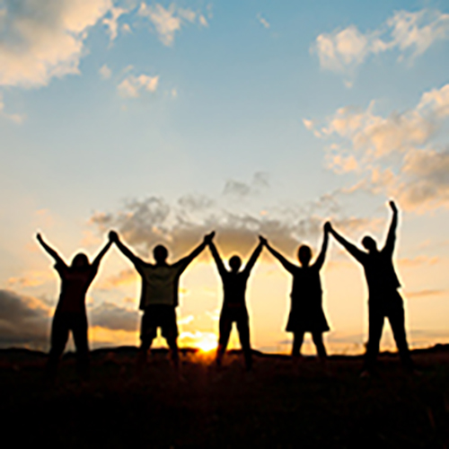 夕焼け空の下、手をつなぎ喜ぶ人々のシルエット画像