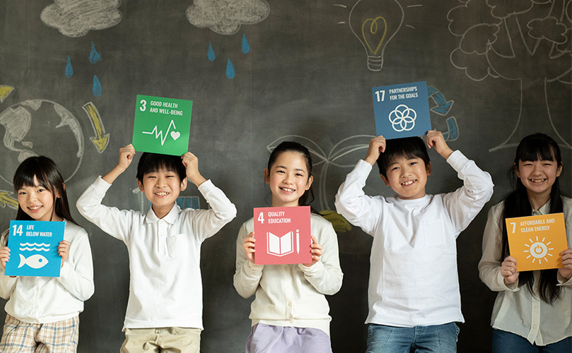 それぞれの SDG カードを持つ、5人の笑顔の子供たち