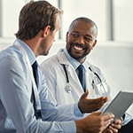 タブレットを手に笑顔で会話する二人の医師