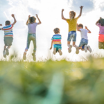 草原で飛び跳ねて遊ぶ子供たちの様子