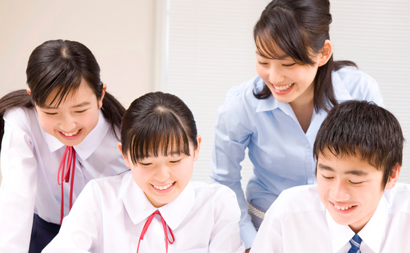 女性の先生が、学習中の生徒たちに指導する様子