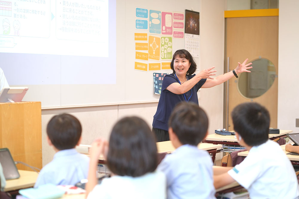 教壇の横に立つ先生と話を聞く子どもたち