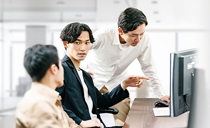 3人の男性がPCを見ながら話し合い