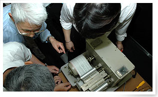 若手に機械の構造を指南するOB。技術の継承はこうして続けられて