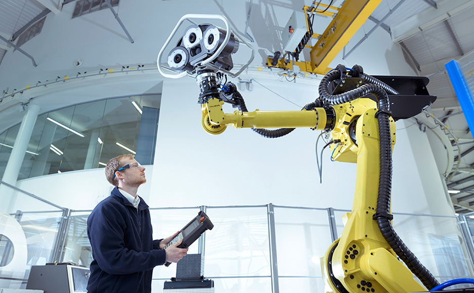 A technician operating a robotic arm in a factory.