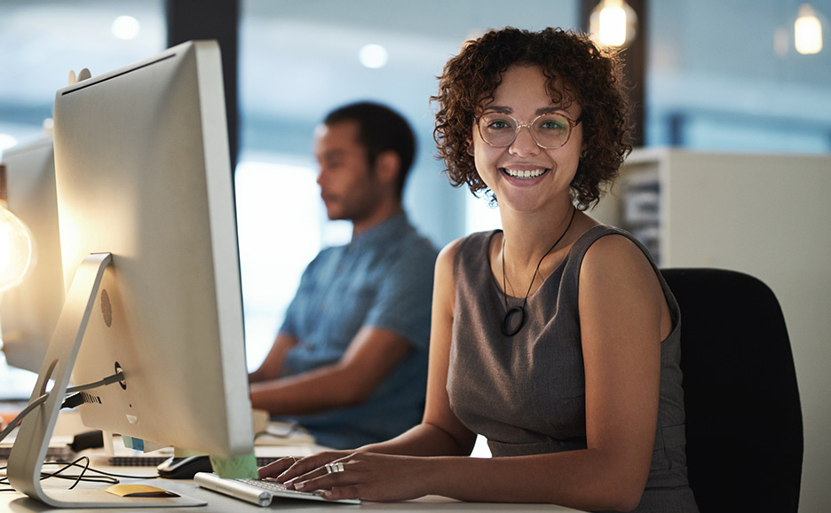 A smiling woman working at a computer in an office