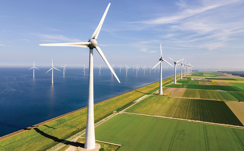 Luftaufnahme von Windkraftanlagen auf einer grünen Wiese und im Wasser