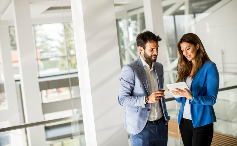 Two people chatting while looking at a tablet