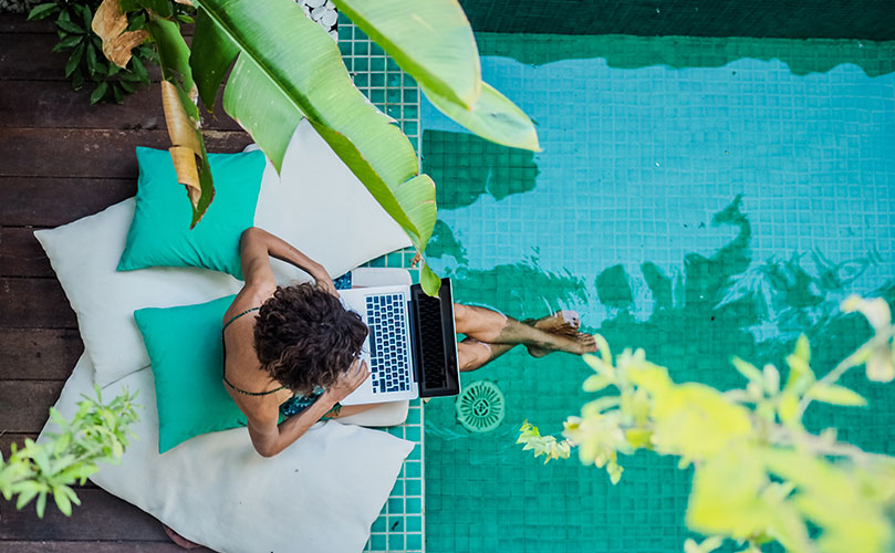 A woman in a swimming pool, working on her laptop.