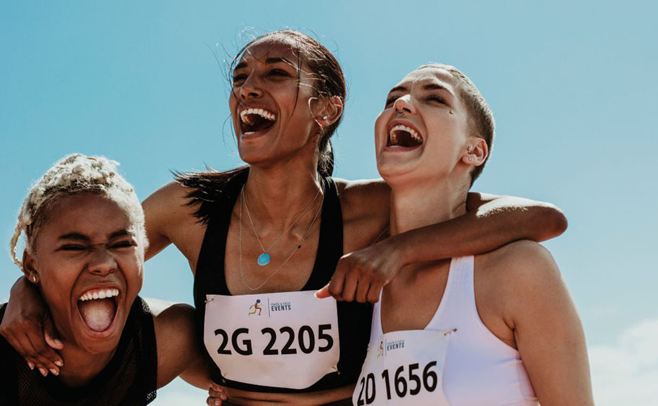Three smiling athletes with arms around each other