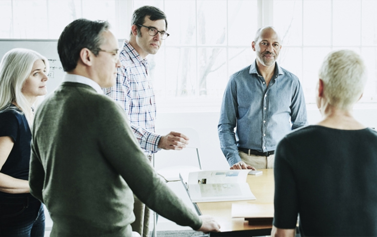 A diverse group of individuals gathered around a table, engaged in conversation and collaboration.