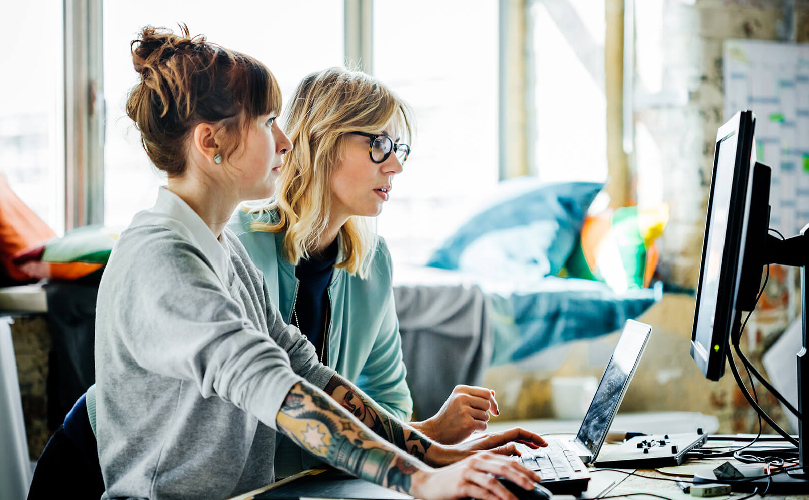 Kollaboration im Arbeitsumfeld mit zwei Frauen und Computertechnik