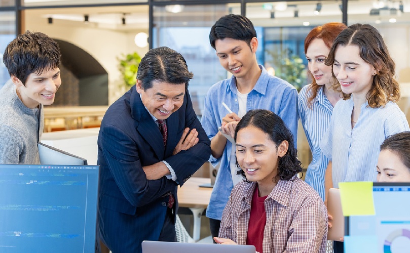Um grupo de pessoas num escritório a olhar para um computador e a sorrir