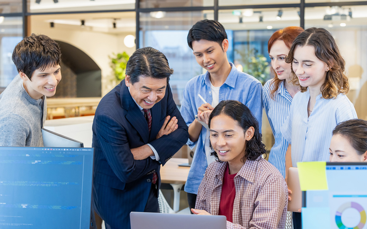 Un grupo de personas en un entorno de oficina mirando un equipo y sonriendo