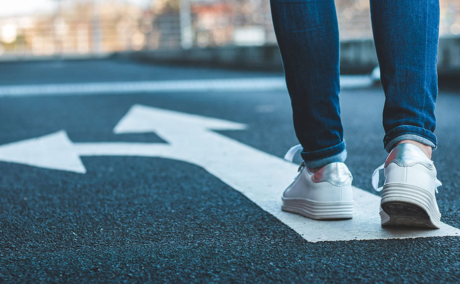 Person's feet walking on road arrow