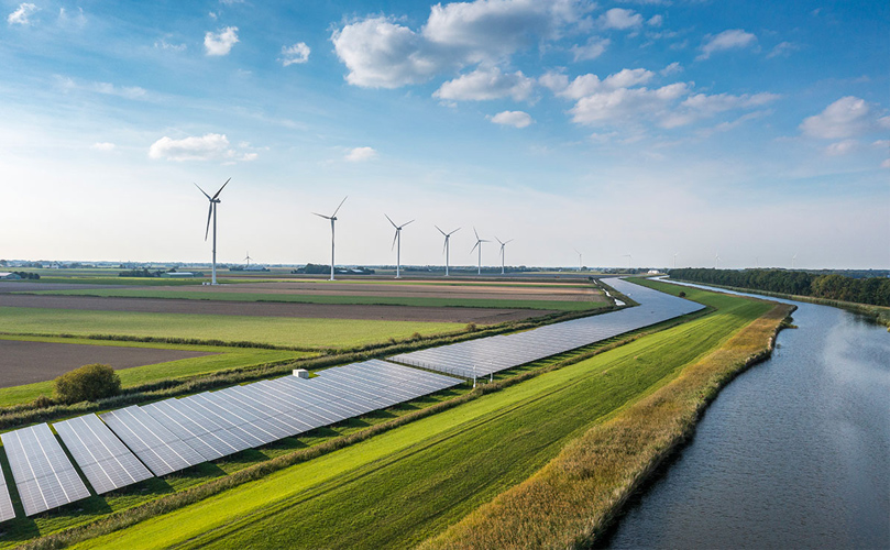 A green field with solar pannels and wind turbines