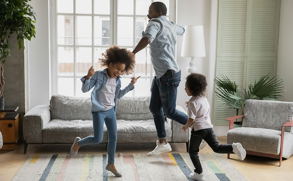 A family jumping together on a rug in a living room.