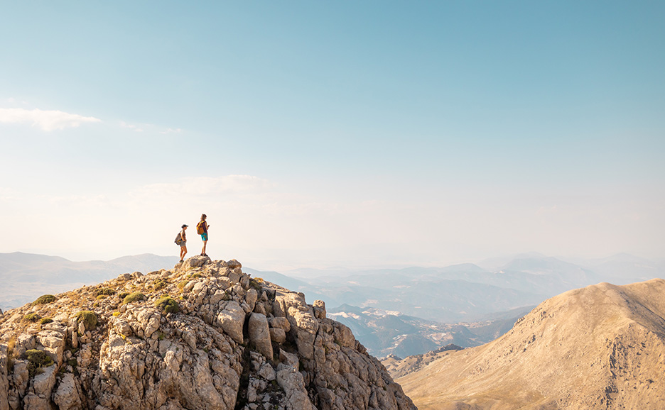 Two hikers standing on a mountain peak.