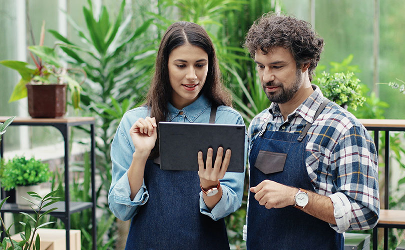 A couple in a garden looking at the tablet.