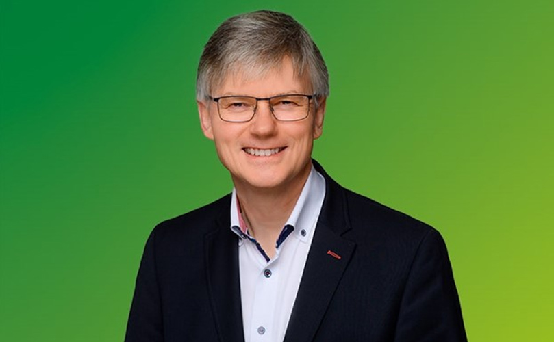 A man smiling to the camera in a green background