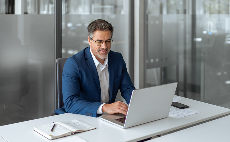 Business woman at her desk in an office looking at her laptop 
