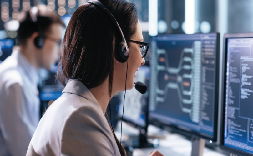 A woman looking at a computer while wearing headphones