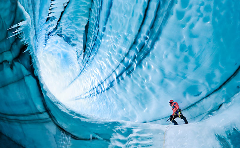 Un homme escaladant une grotte de glace